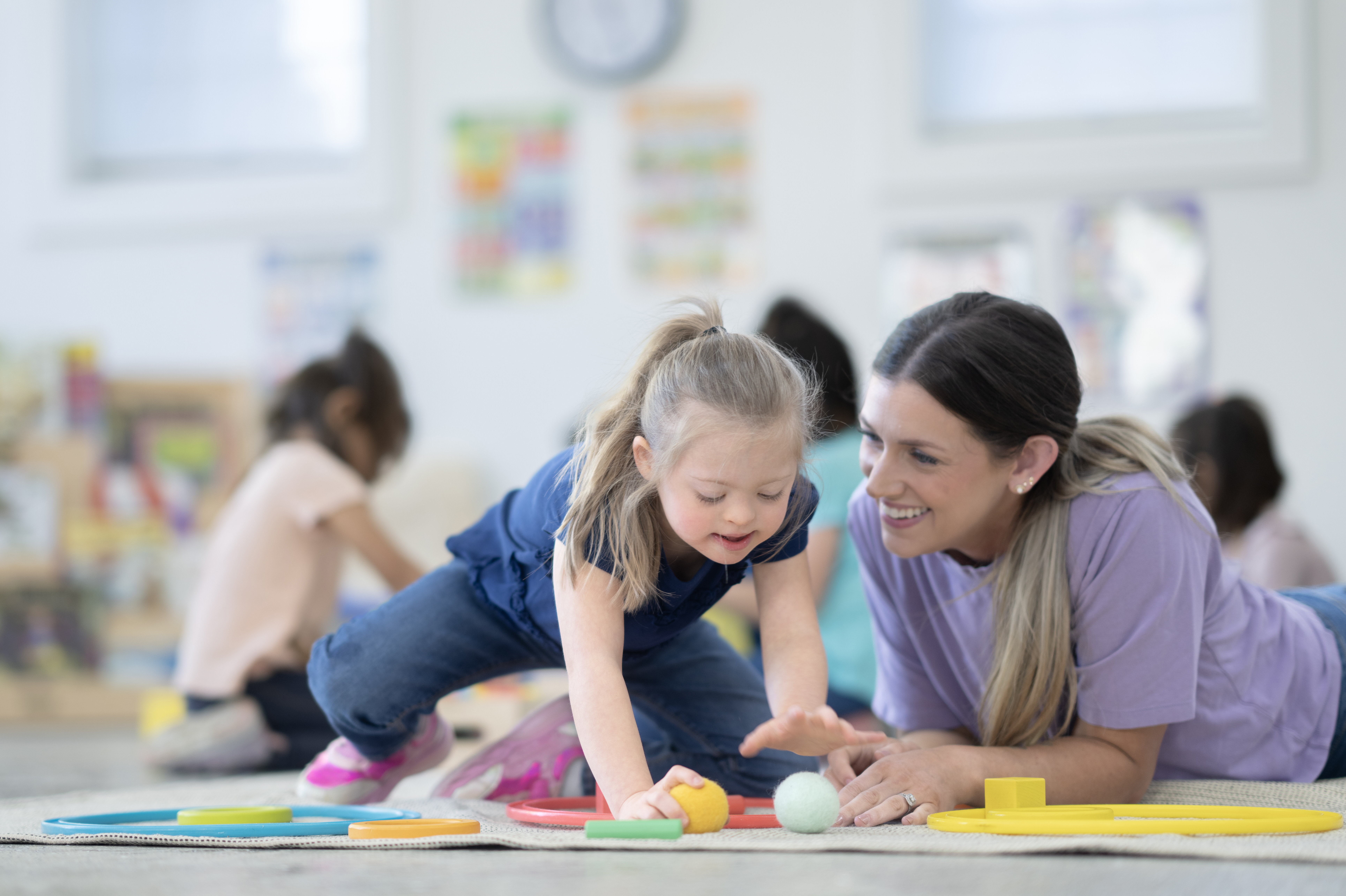 Mädchen und Betreuerin spielen gemeinsam mit bunten Bällen