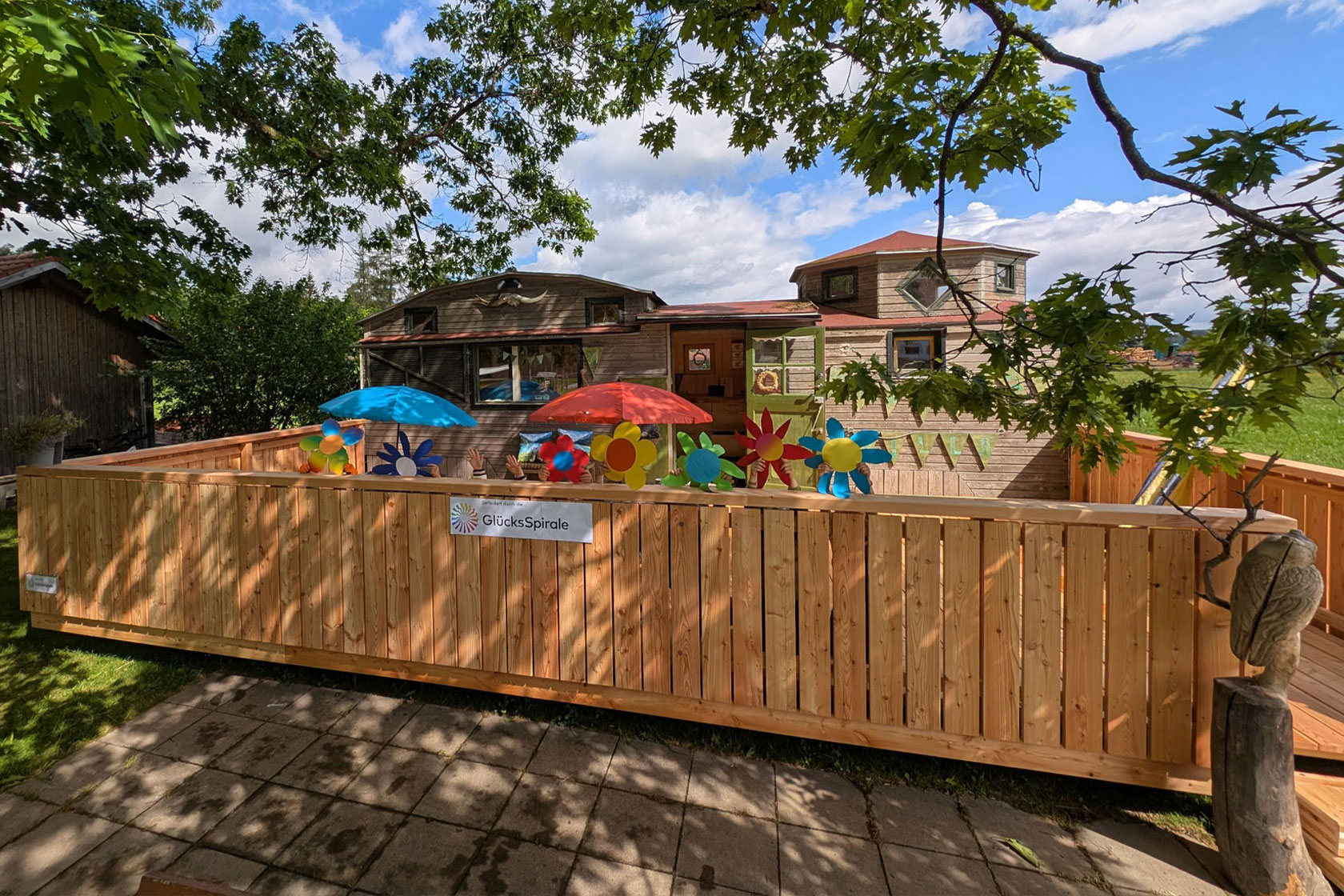 Die Holzterrasse der Kräutervilla fügt sich optisch hervorragend in den schönen Garten des AWO Kinderhauses Osterzell ein. Hier können Kinder an der frischen Luft Kräuter und Blumen pflanzen und Natur hautnah erleben. Foto: AWO Schwaben